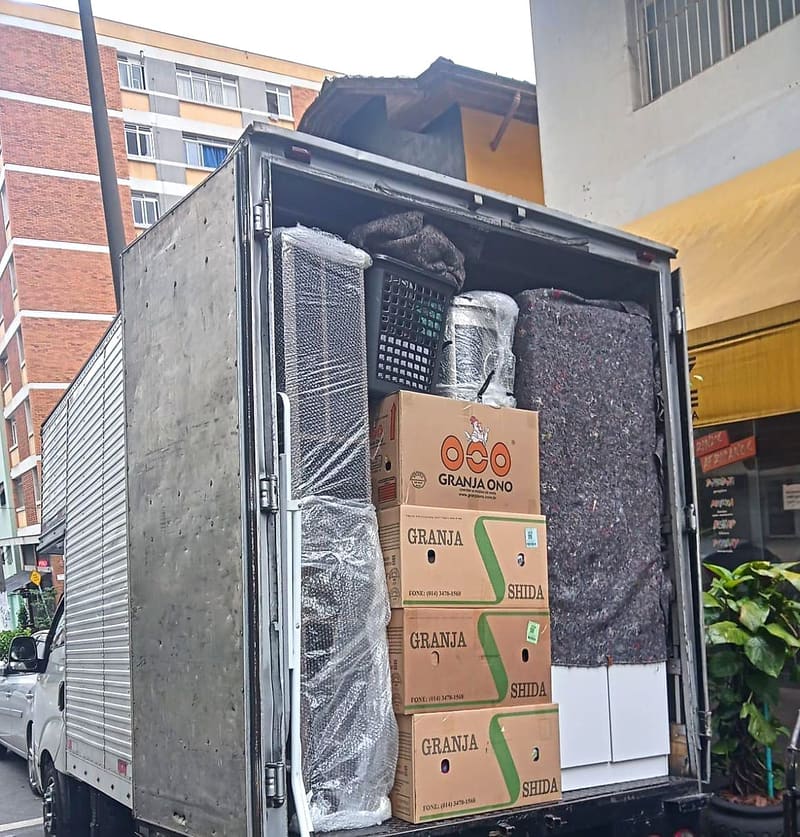 Caixas empilhadas e móveis protegidos dentro do caminhão da Villa Transportes