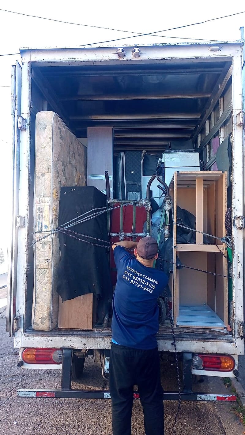 Funcionário da Villa Transportes de camiseta azul amarrando a carga no caminhão